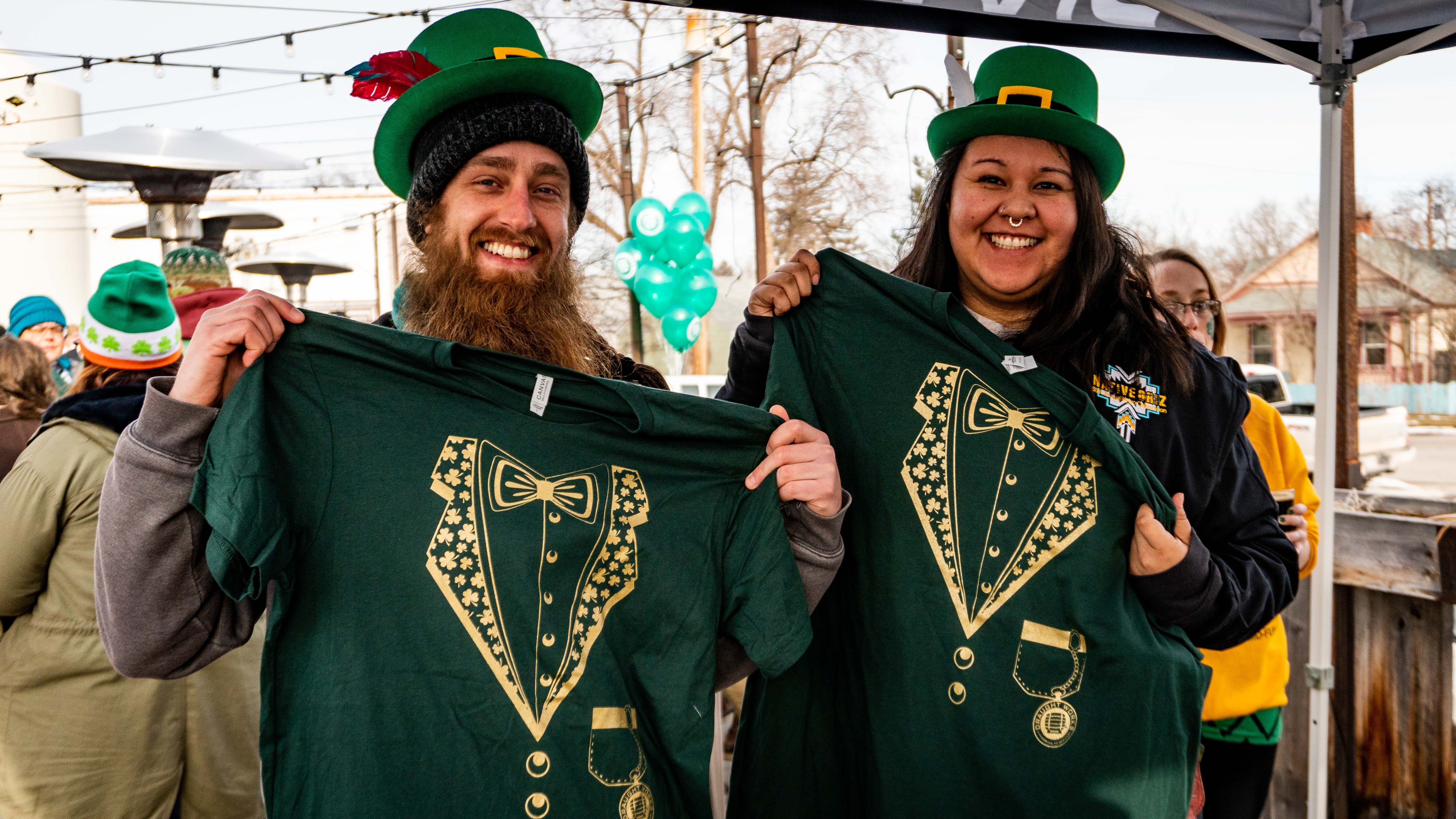 Two happy Draught Works customers hold up their free St. Paddy's Day t-shirts from 2019.