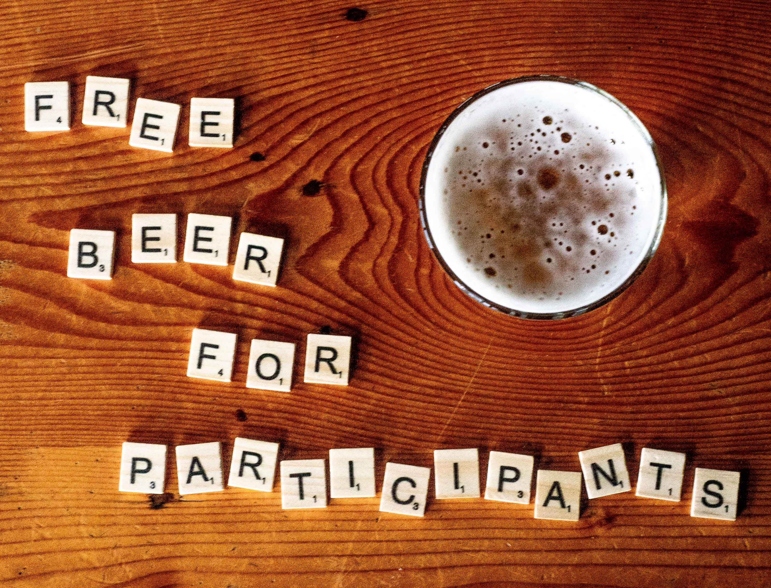 'FREE BEER FOR PARTICIPANTS' spelled out in Scrabble letters next to a pint of Draught Works beer.